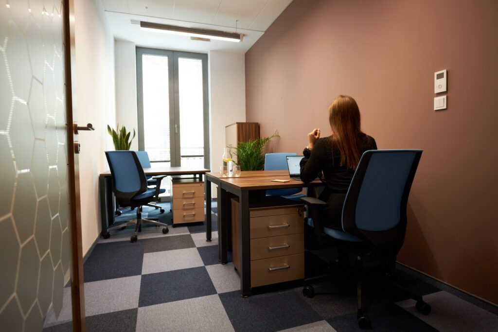 Osoba pracuje przy biurku w małym gabinecie Workin