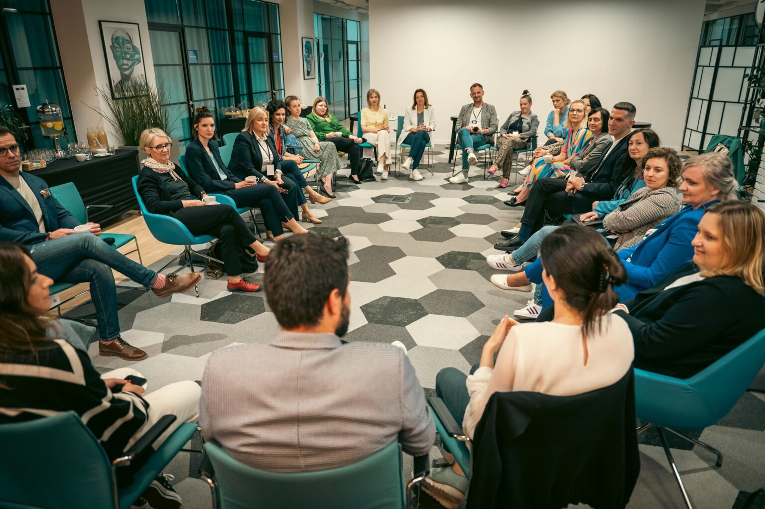 Workshop participants seated in a large U-shape in the Workin event space